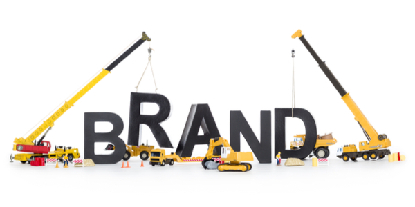 Heavy-duty machinery building the word "brand" to represent the concept of "brand building" or "crear una marca".