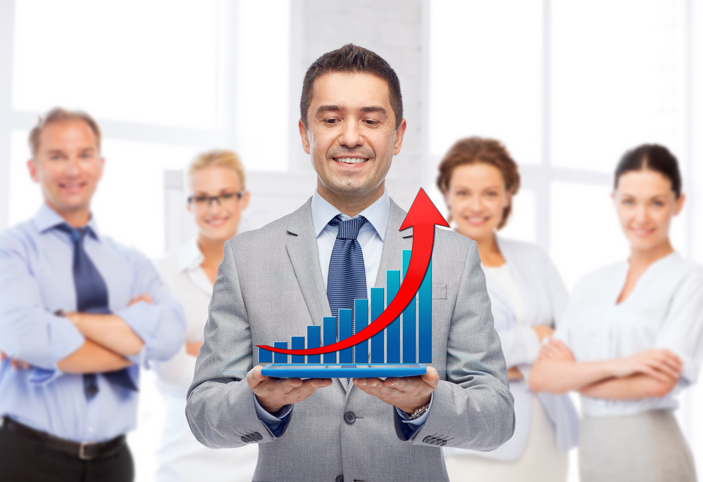 Hispanic sales team with member holding a sales graphic